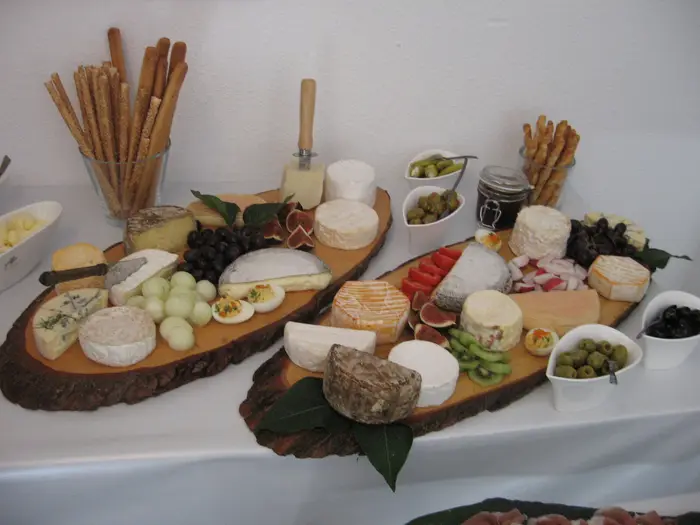 Käsebrett auf Holzscheibe mit Trauben und Brot